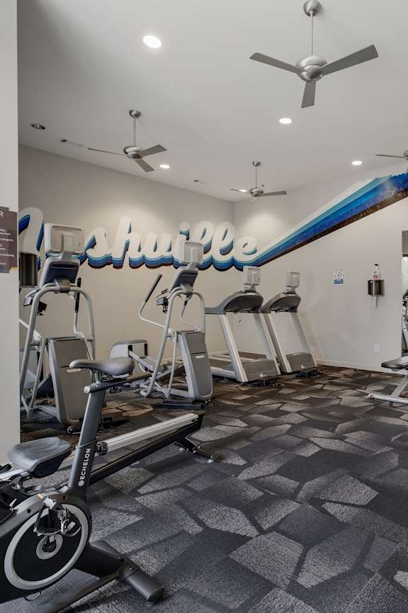 a gym with cardio equipment and weights on the floor