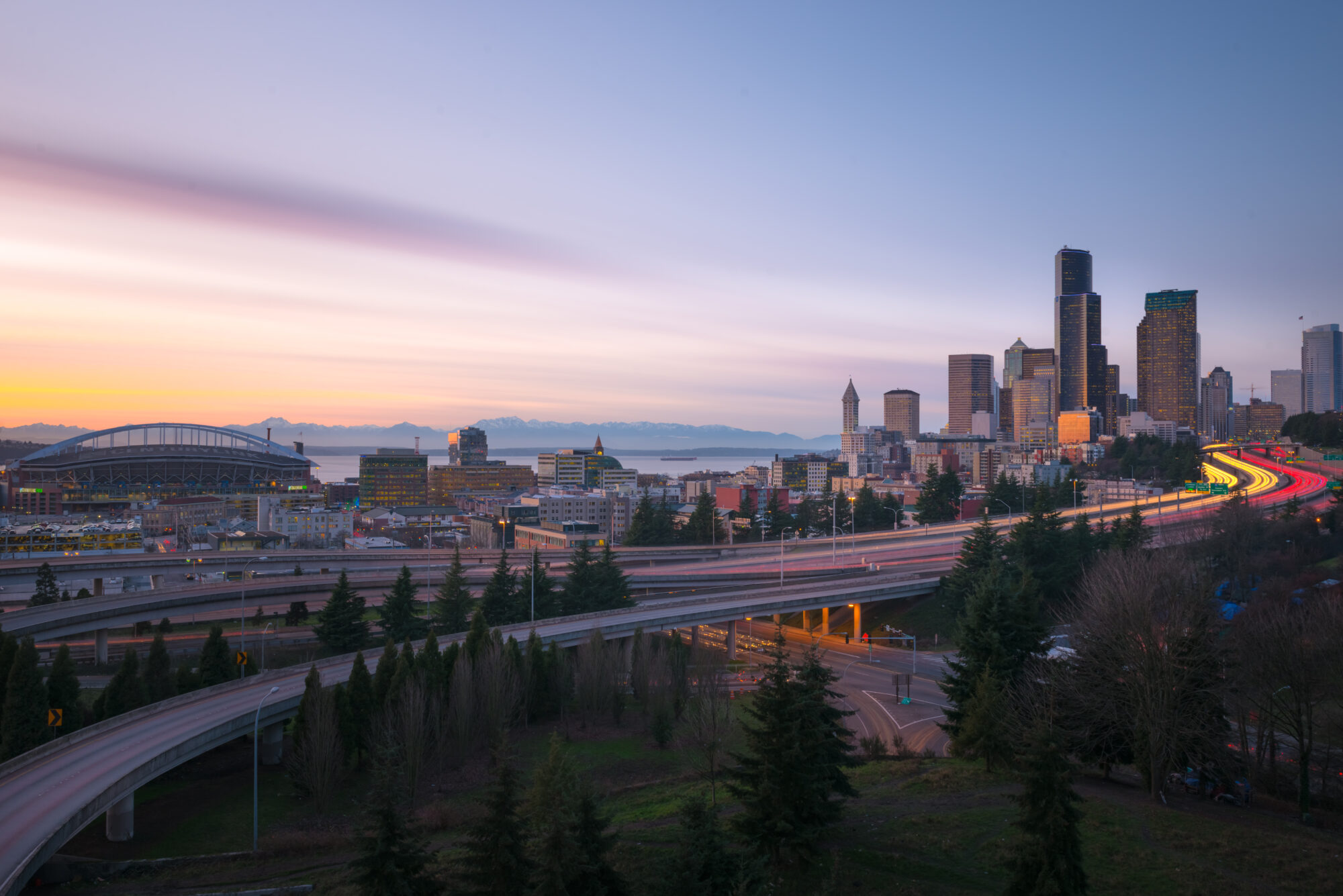City skyline with highway, mountains in the distance