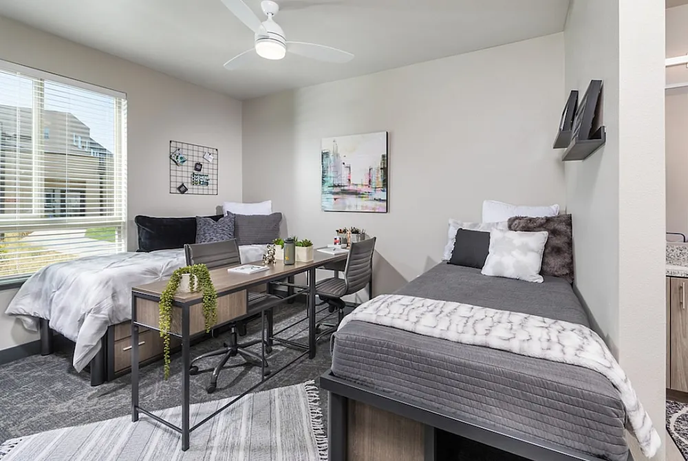Model bedroom at Hornet Commons apartments in Sacramento, CA, featuring carpeted flooring and two beds.