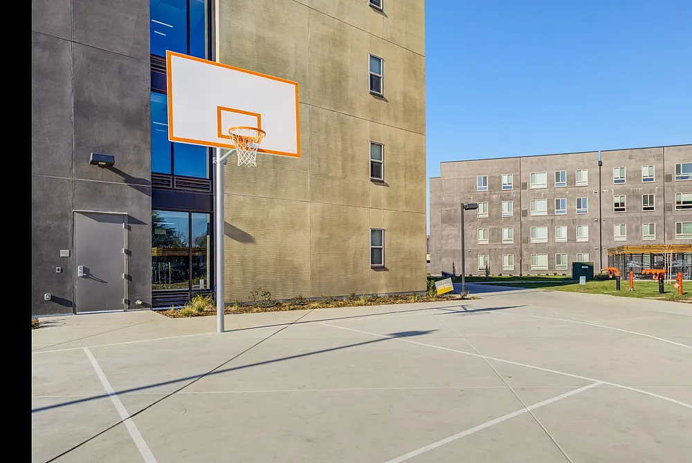 The basketball courts at Hornet Commons apartments in Sacramento, CA, featuring a view of the apartment exteriors.
