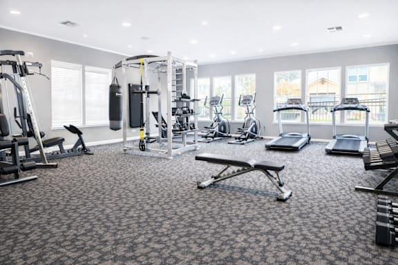 A spacious gym with a variety of equipment including treadmills, stationary bikes, and weight machines.