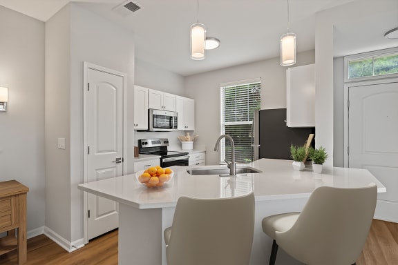 a kitchen with white cabinets and a white island with a bowl of fruit on it at Fortress Grove, Tennessee, 37128