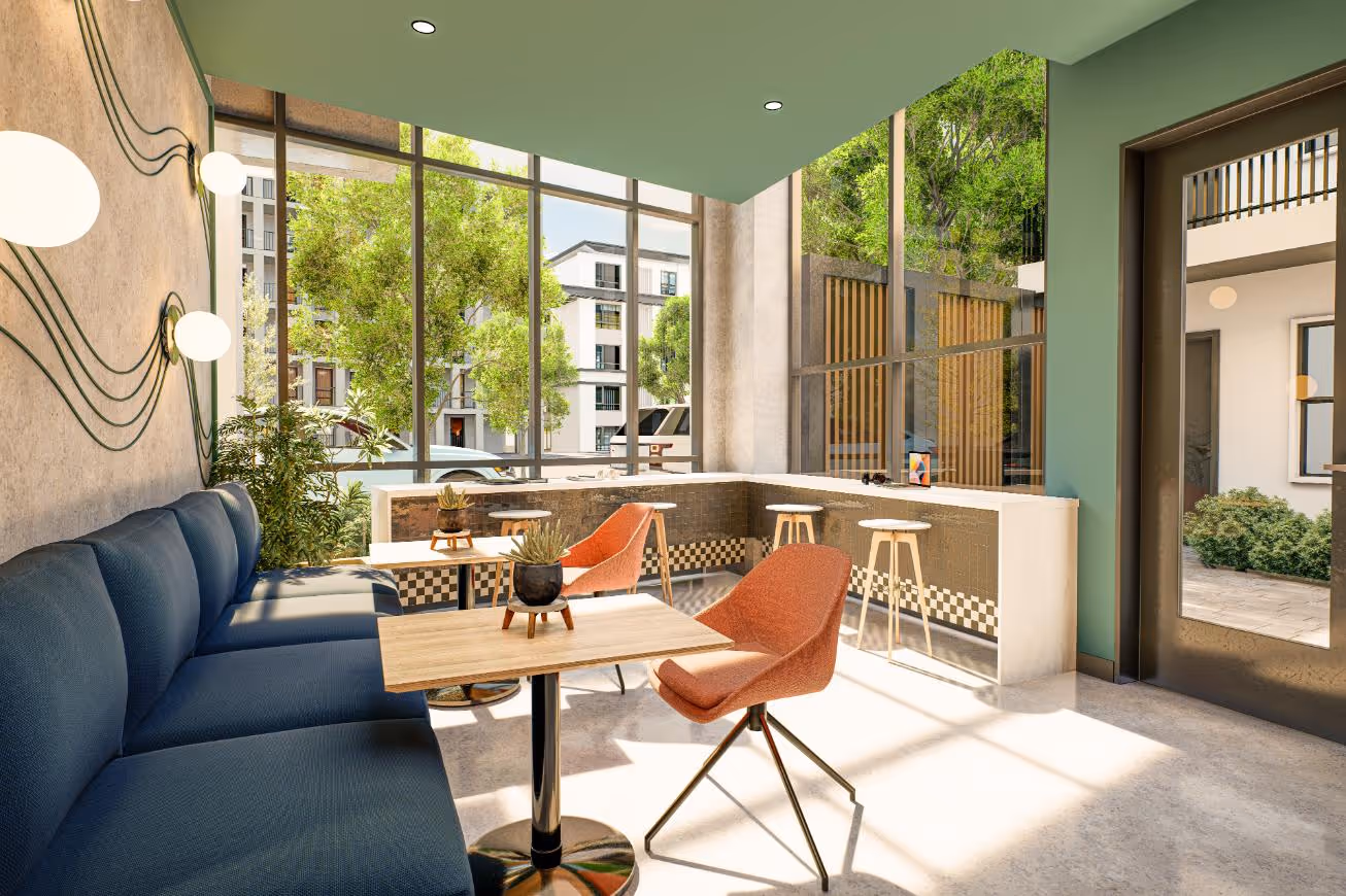 The indoor community lounge with floor-to-ceiling windows offering views of the exterior. The space features a long navy blue built-in couch, wooden tables, and a breakfast bar with modern stools.