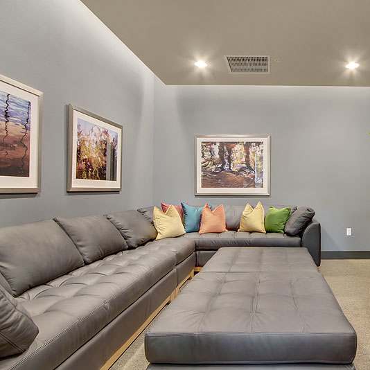 A living room with a grey couch and a television on the wall.