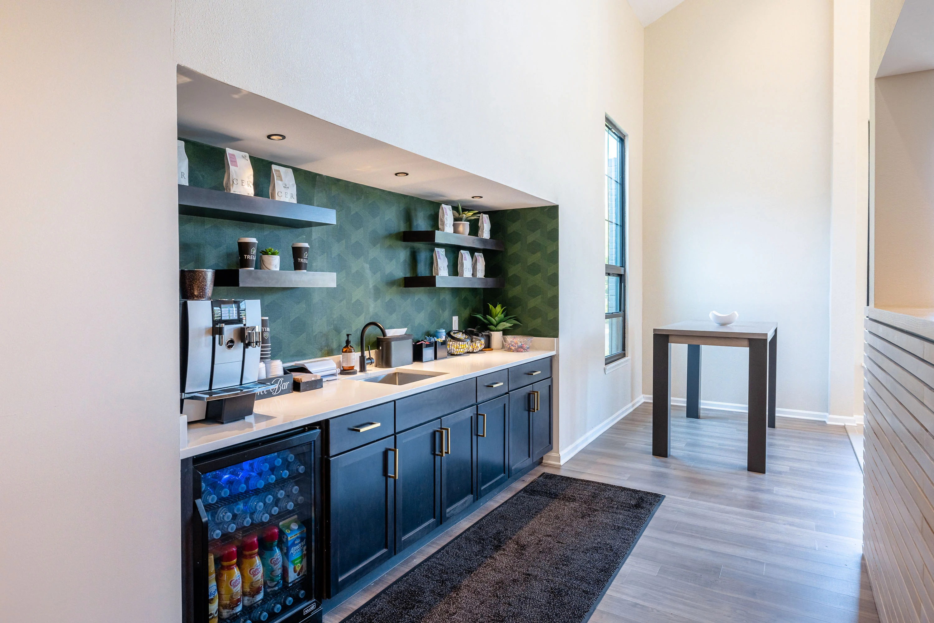 Clubhouse kitchen with dark cabinets, stone countertops, coffee bar, and mini fridge with drinks