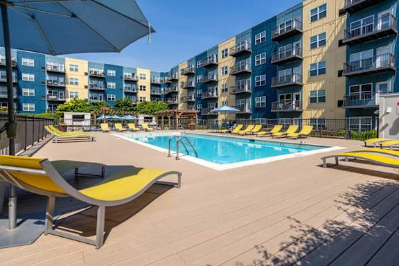a pool with yellow chairs and an umbrella next to an apartment building at Wheaton 121, Wheaton, 60187