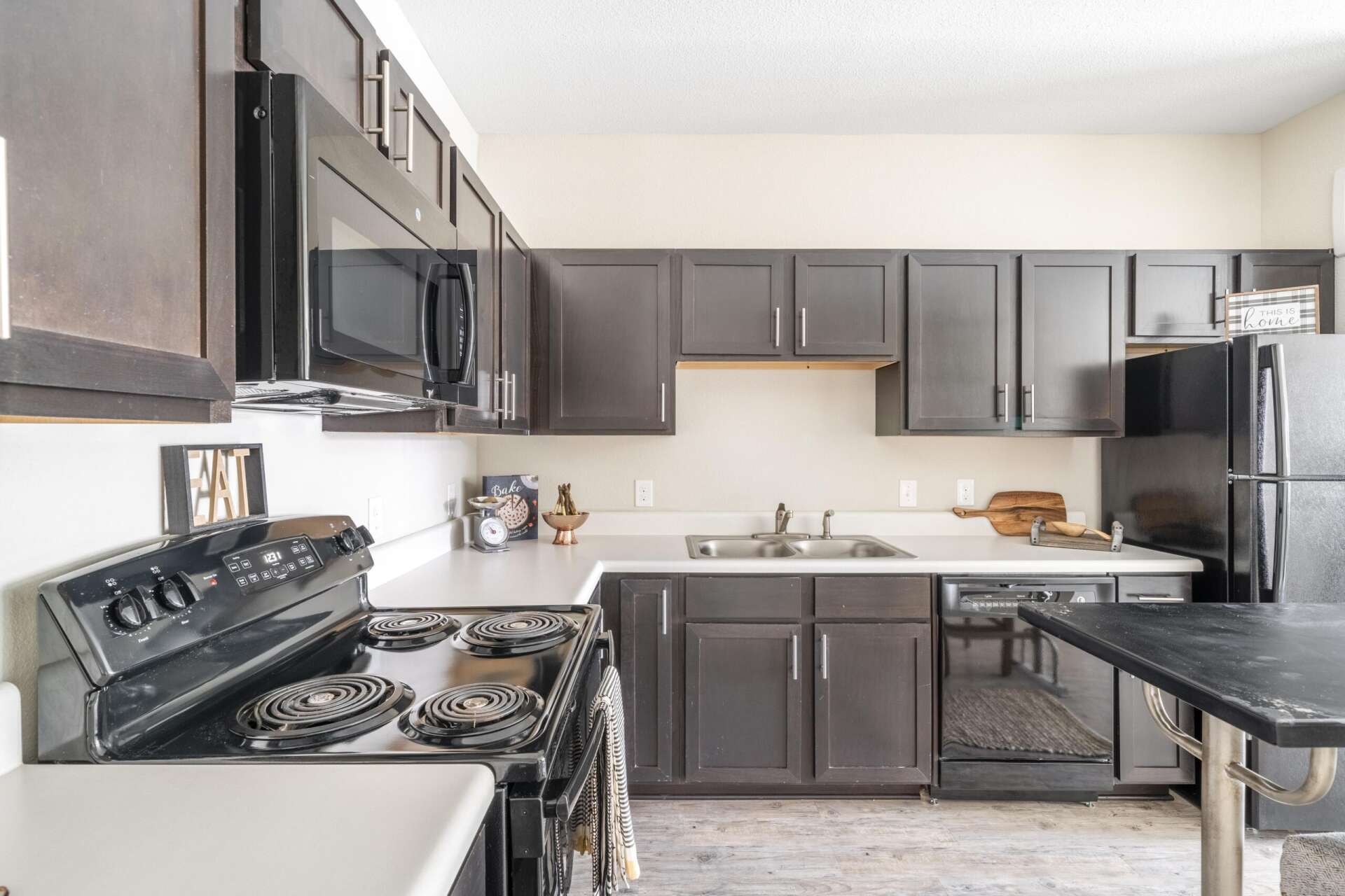 A kitchen at Villages at Fiskville equipped with black appliances, espresso cabinets, and white countertops.
