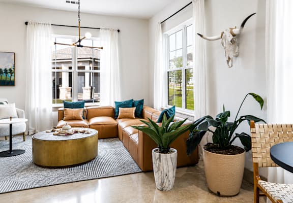 A living room with a white couch, a round coffee table, and a cow skull on the wall.