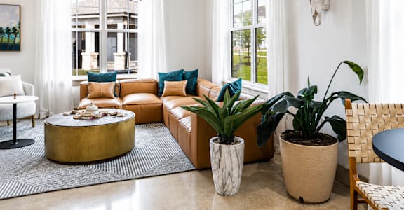 A living room with a white couch, a round coffee table, and a cow skull on the wall.
