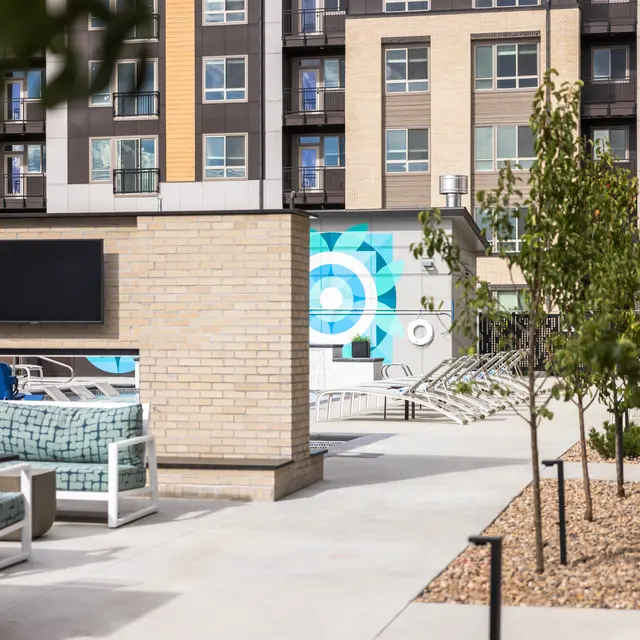 Outdoor community space with a pool and lounging area, featuring modern seating and a decorative wall.