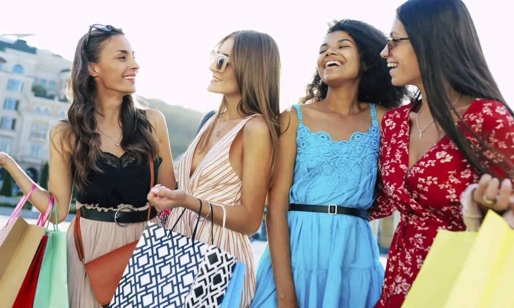 four women with shopping bags looking at each other