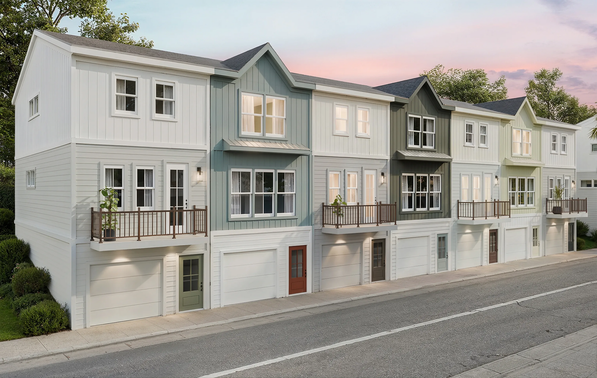 Row of pastel modern townhouses along a quiet street at sunset