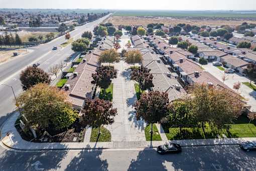 an aerial view of a parking lot with cars and trees