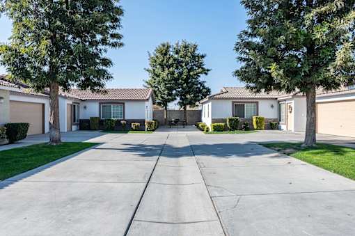 a street with houses and trees and a cement driveway