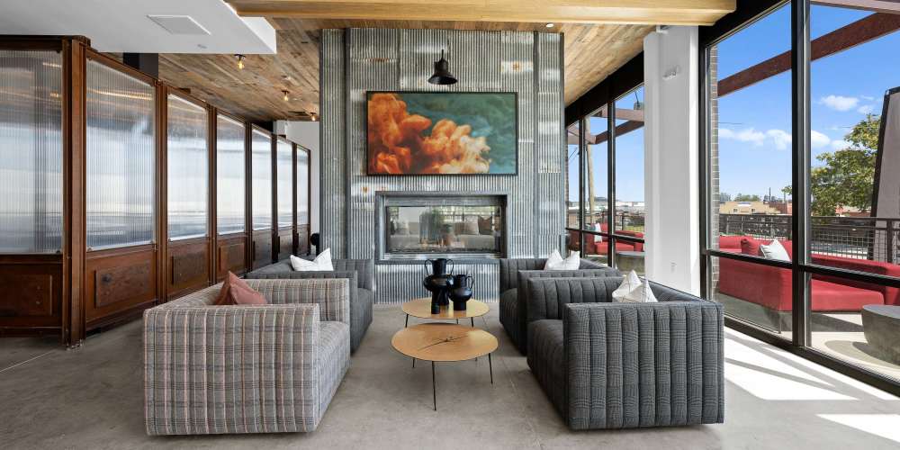 A modern lounge area with four gray armchairs, a coffee table, and a fireplace at Ironworks on Fox in Denver, Colorado