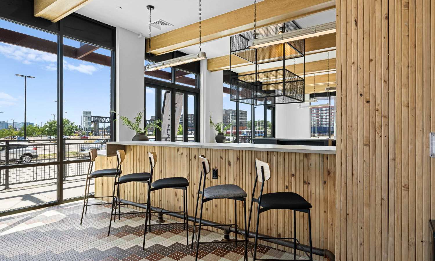A bar area with wooden paneling, high chairs, and large windows at Ironworks on Fox in Denver, Colorado