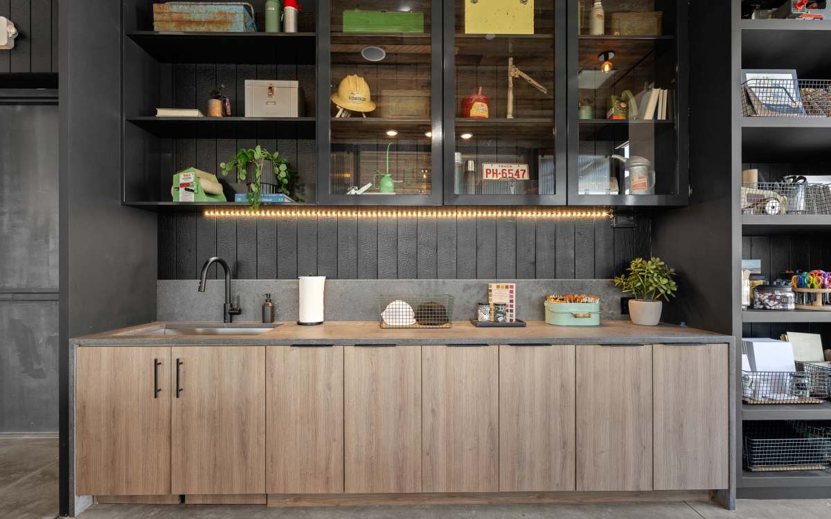 A modern workspace with a sleek countertop and sink, light wood lower cabinets, black upper shelves at Ironworks on Fox in Denver, Colorado
