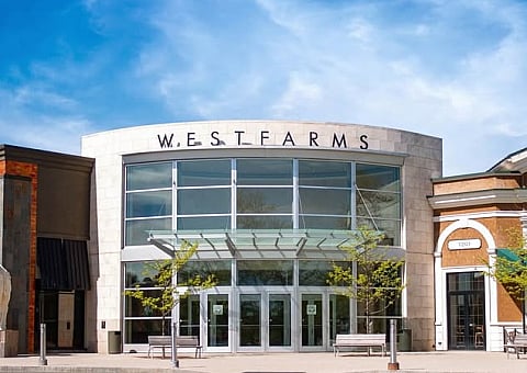 Vibrant exterior of Westfarms showcasing modern architecture, stylish storefronts, and inviting outdoor seating under a clear blue sky.