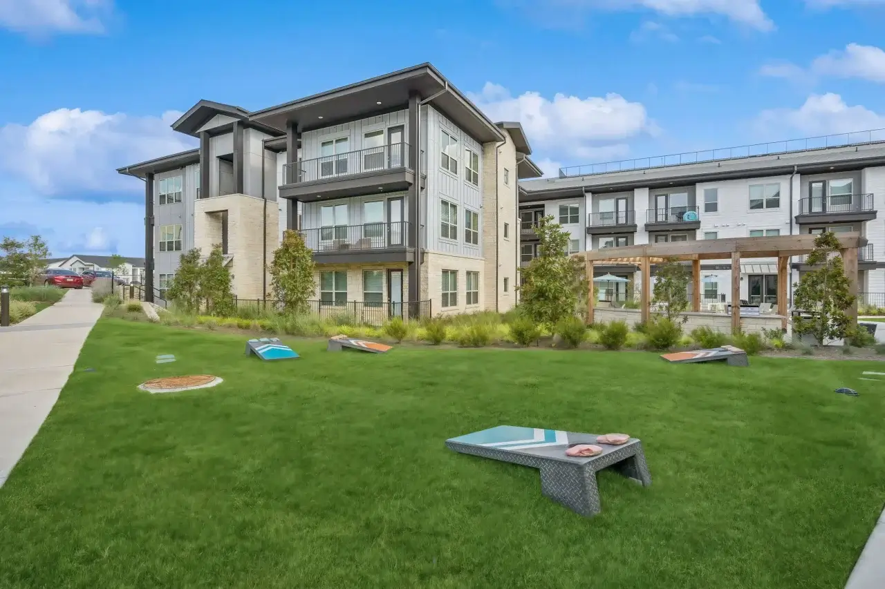 Inviting green space at Ascend at the Parkway apartments in katy featuring a corn hole game, perfect for gathering with neighbors and relaxing outdoors.