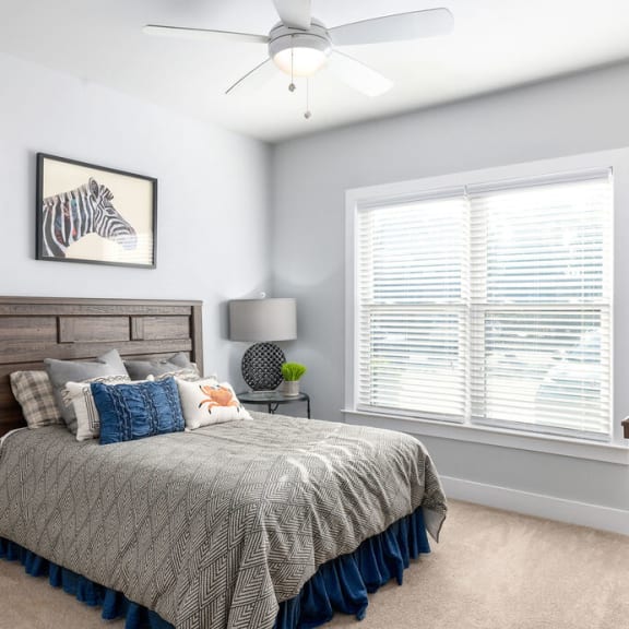 a bedroom with a large window and a ceiling fan
