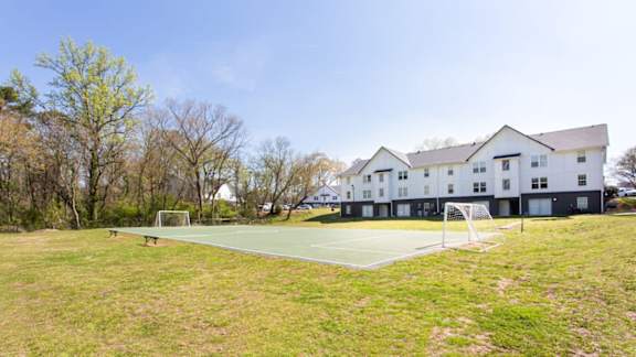 A tennis court is located in front of a white building.