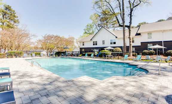 A large swimming pool surrounded by a tiled patio and a white house in the background at Barcelo at East Cobb Apartments, Marietta, GA, 30067