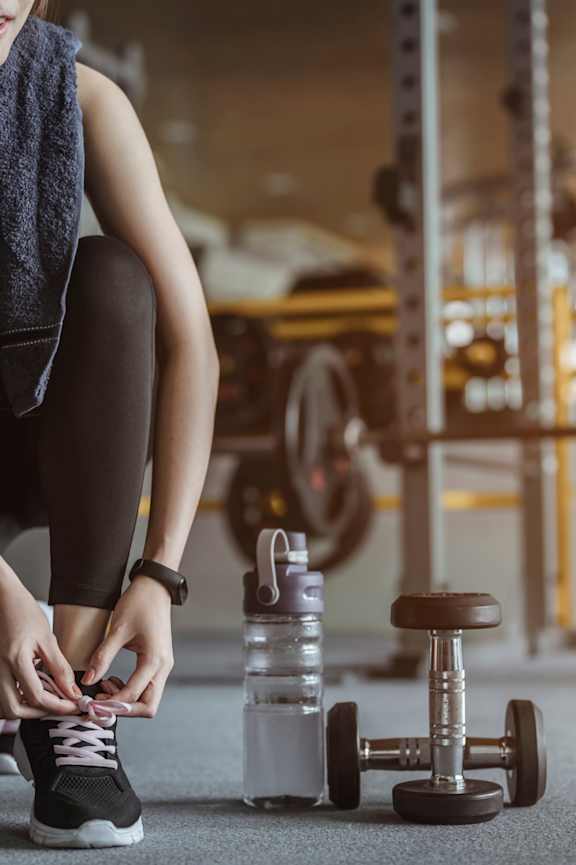A woman tying her shoelaces in a gym.