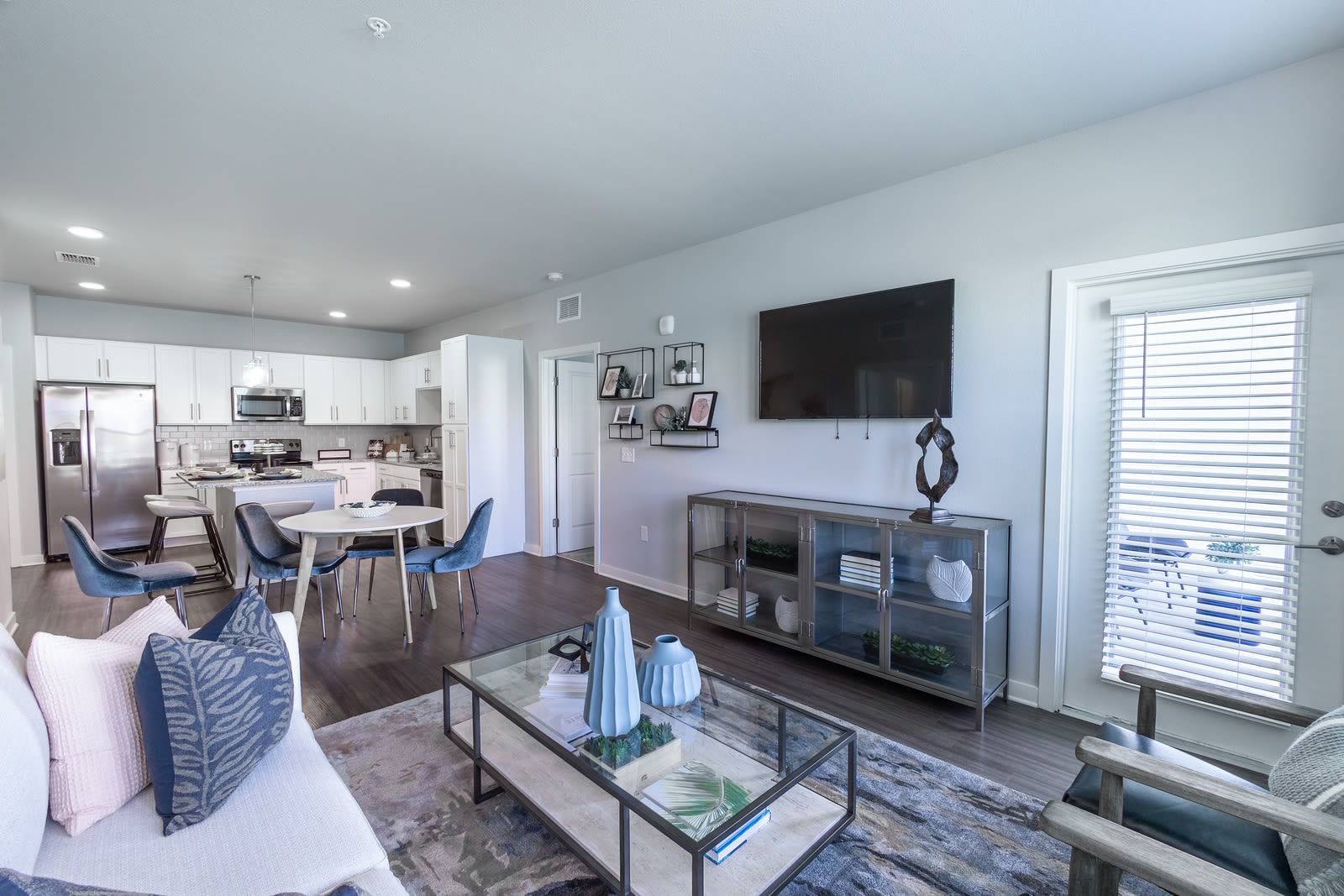Open layout living room with couch, television, coffee table connected to kitchen area at Indigo Champions Ridge in Davenport, Florida