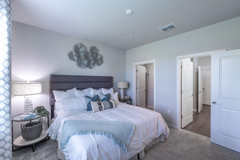 Bedroom with comfortable bed with bed lamp and attached closet at Indigo Champions Ridge in Davenport, Florida