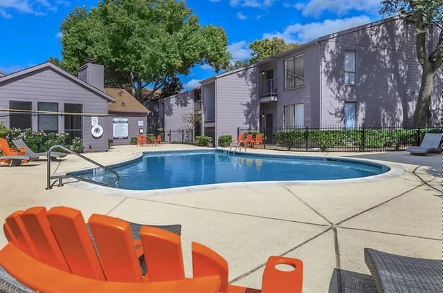 Outdoor swimming pool with lounge chairs and trees.
