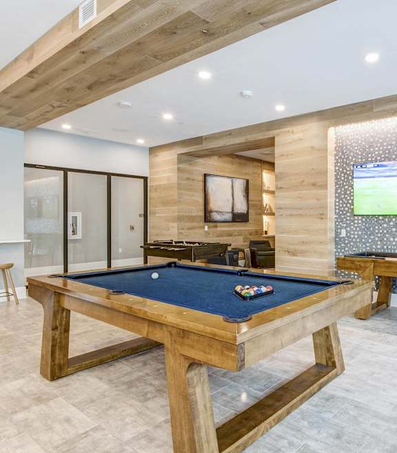 A pool table in a room with a TV and a bench at Mayla Pompano Beach, Pompano Beach, 33062