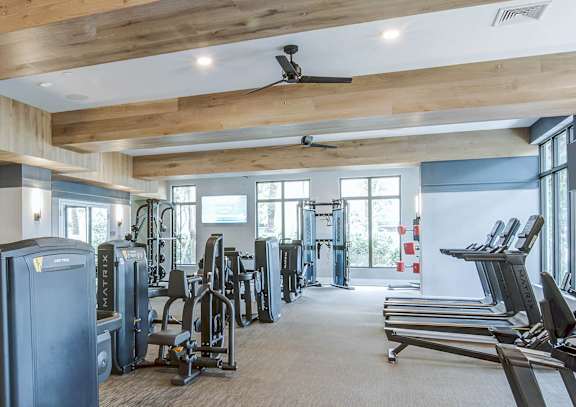 A gym with a variety of equipment including treadmills, weights, and exercise machines at Mayla Pompano Beach, Pompano Beach