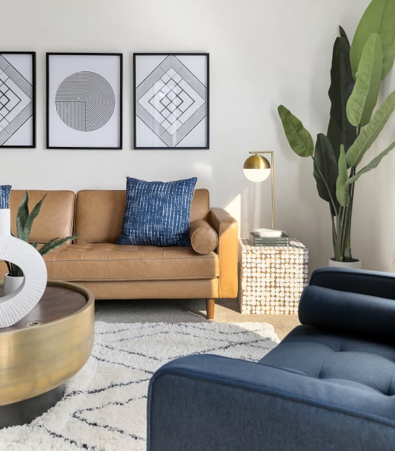 a living room with a brown couch and a blue chair at Mosaic on the River Apartments, Richland