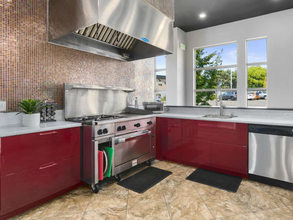 a kitchen with red cabinets and stainless steel appliances at Mosaic on the River Apartments, Richland, Washington
