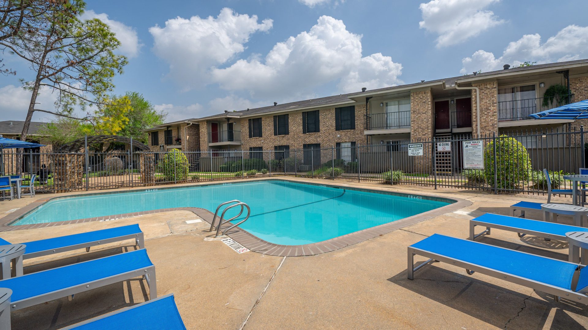 Sparkling swimming pool with sun deck and brick apartment buildings at Clear Creek Landing in Houston, TX