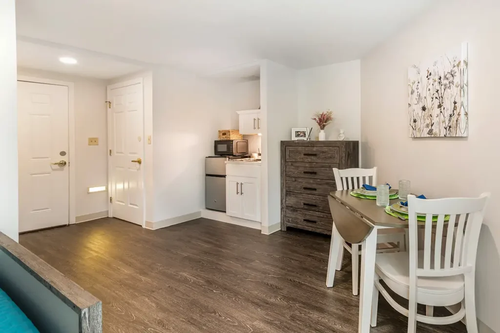 furnished apartment at Charter Senior Living of Dedham with table and chairs, dresser, sink, mini fridge, and microwave