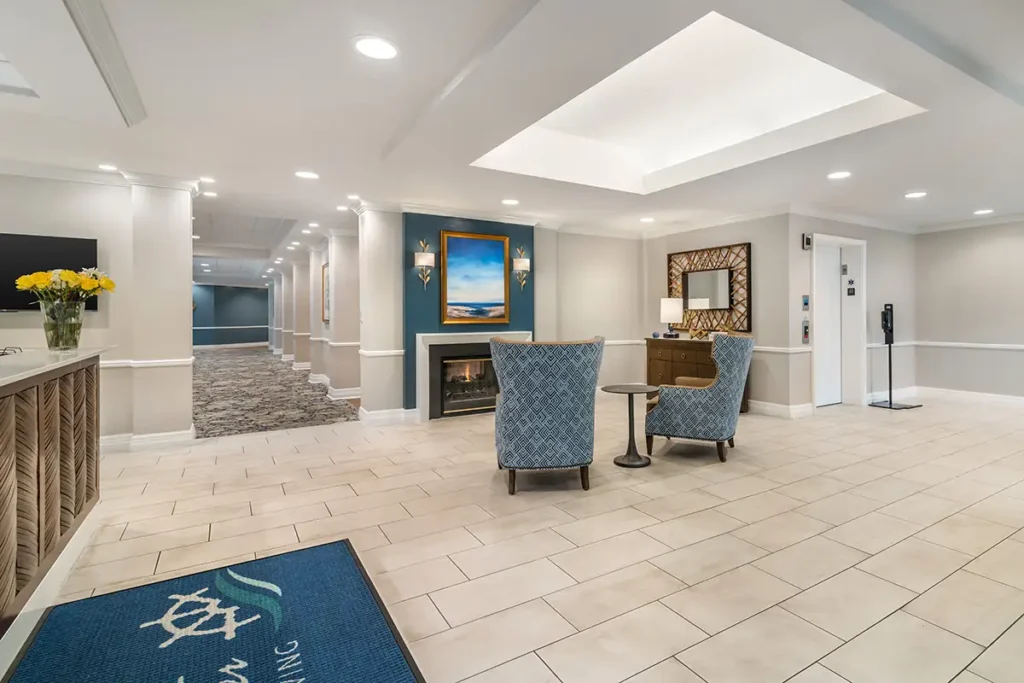 reception desk area with chairs and a fireplace at Charter Senior Living of Dedham