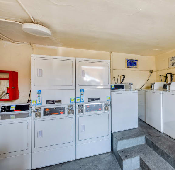 a row of washing machines in a laundry room with other machines