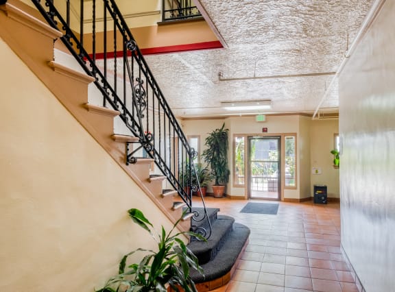a lobby with a staircase and a glass door    and plants