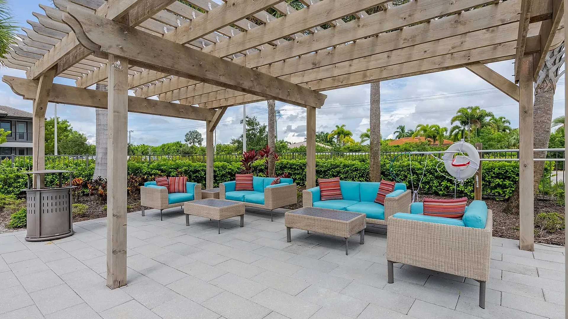 A cozy outdoor lounge area with turquoise seating under a wooden pergola.