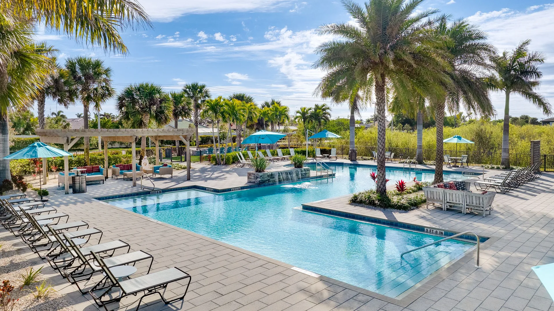 A serene pool area surrounded by palm trees and lounge chairs, perfect for relaxation.