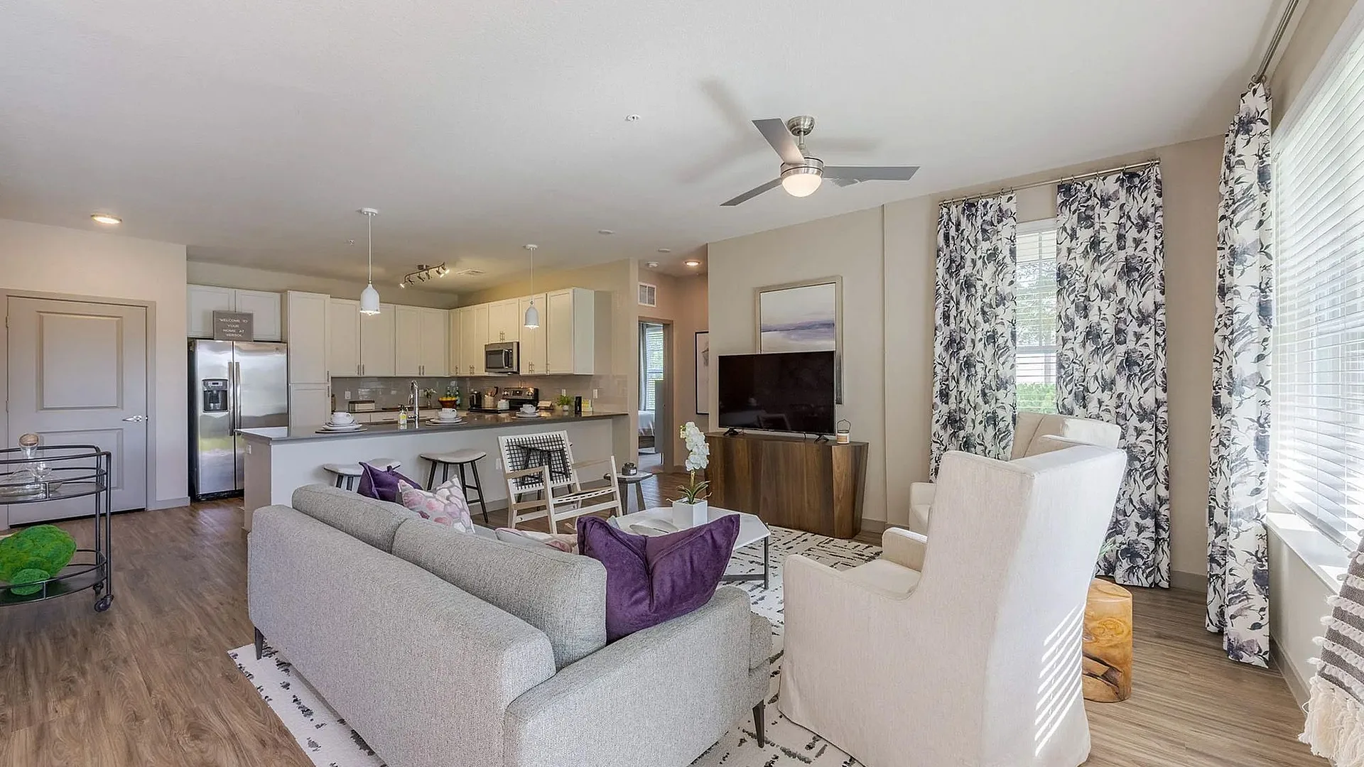A modern living room with a cozy sofa, armchair, and open kitchen area.