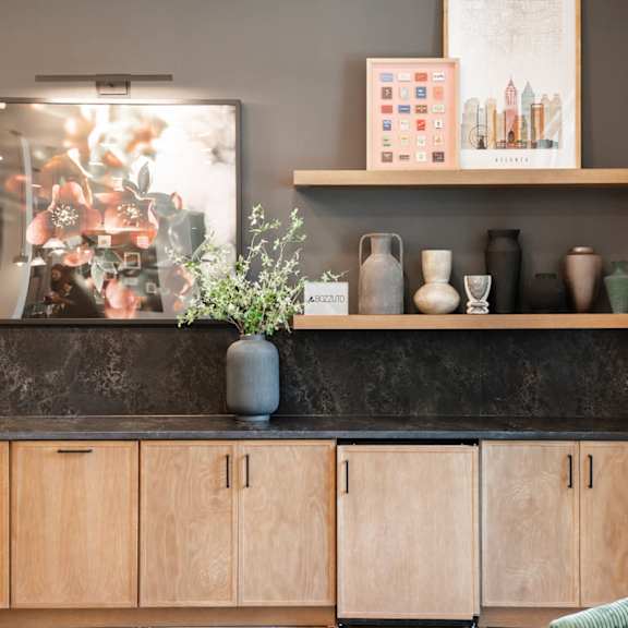 A kitchen with wooden cabinets and a grey countertop with a vase on it.