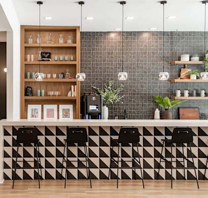 A black and white checkered bar with a green sofa and a wooden shelf above it.