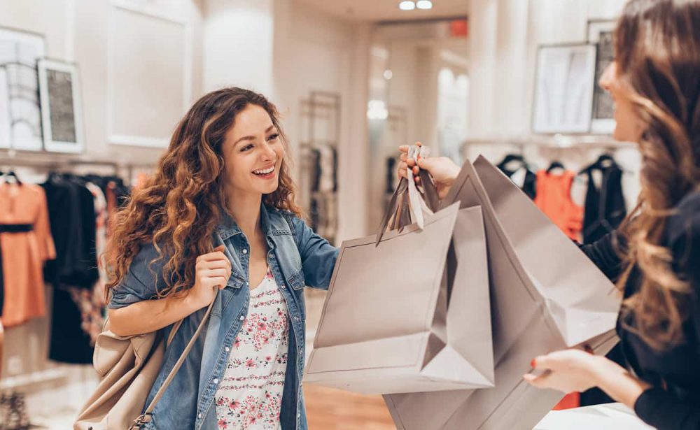 Smiling woman receiving shopping bags from a store clerk.