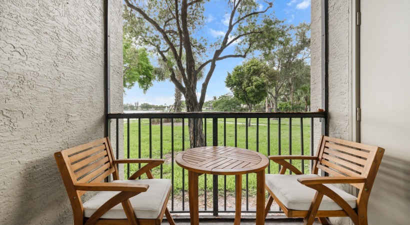 A patio with a table and two chairs overlooking a green lawn.