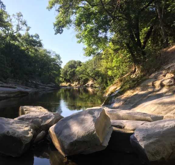 River with rocks and trees on the side of it at AVIA Apartments On Alpha, Dallas, 75240