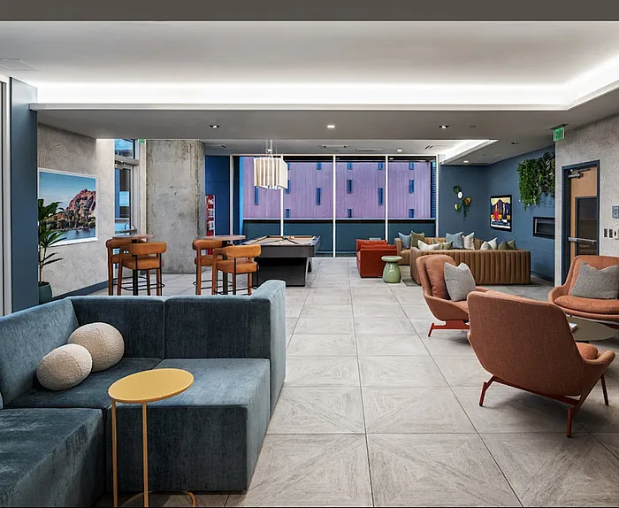 Modern community living space with stylish furniture, a billiard table, and vibrant decor, ideal for relaxation and socializing.