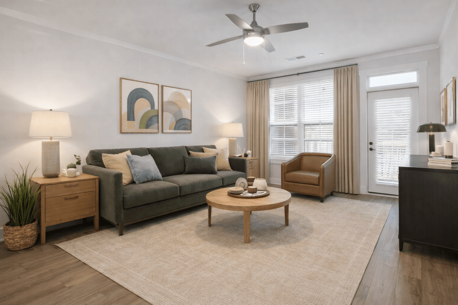 Furnished one-bedroom apartment living area in Charlotte, NC, showing an open layout, ceiling fan, and access to a personal balcony.