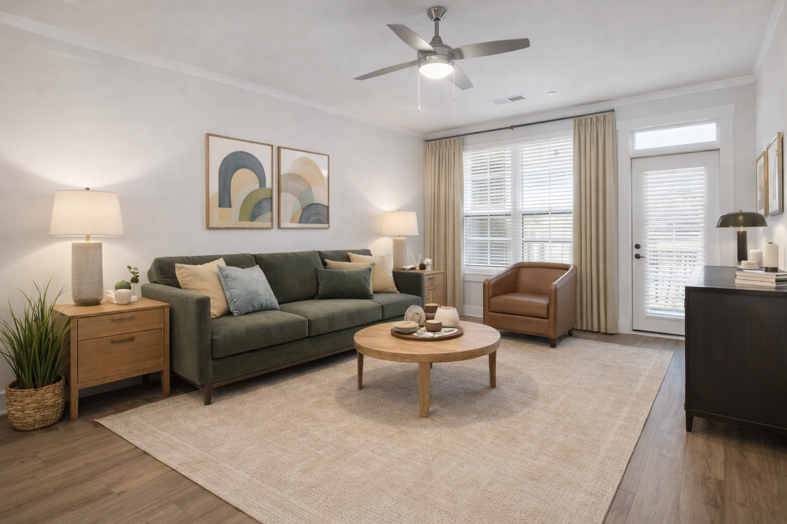 Furnished one-bedroom apartment living area in Charlotte, NC, showing an open layout, ceiling fan, and access to a personal balcony.